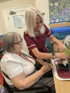 Resident and carer arranging flowers together at a table