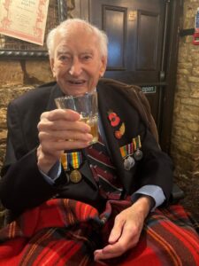 A resident enjoys a drink in a pub in Cirencester. He has a blanket tucked around his legs.