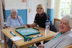 Residents and staff member enjoying a game of scrabble at Watermoor House Residential Care Home