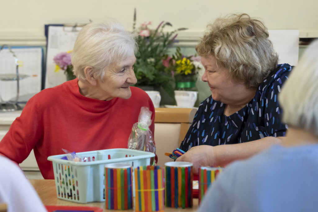 A resident and staff member share a joke during an activity